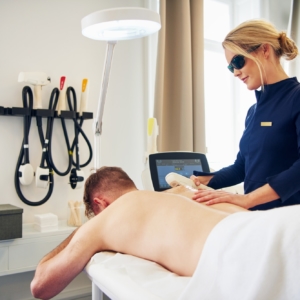 Beautician performing laser hair removal on a male client