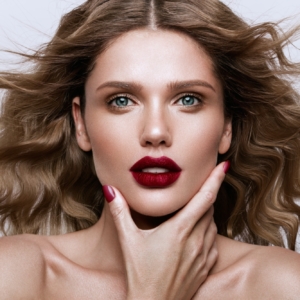 Beautiful face of a fashion model with blue eyes.Curly hair. Red lips